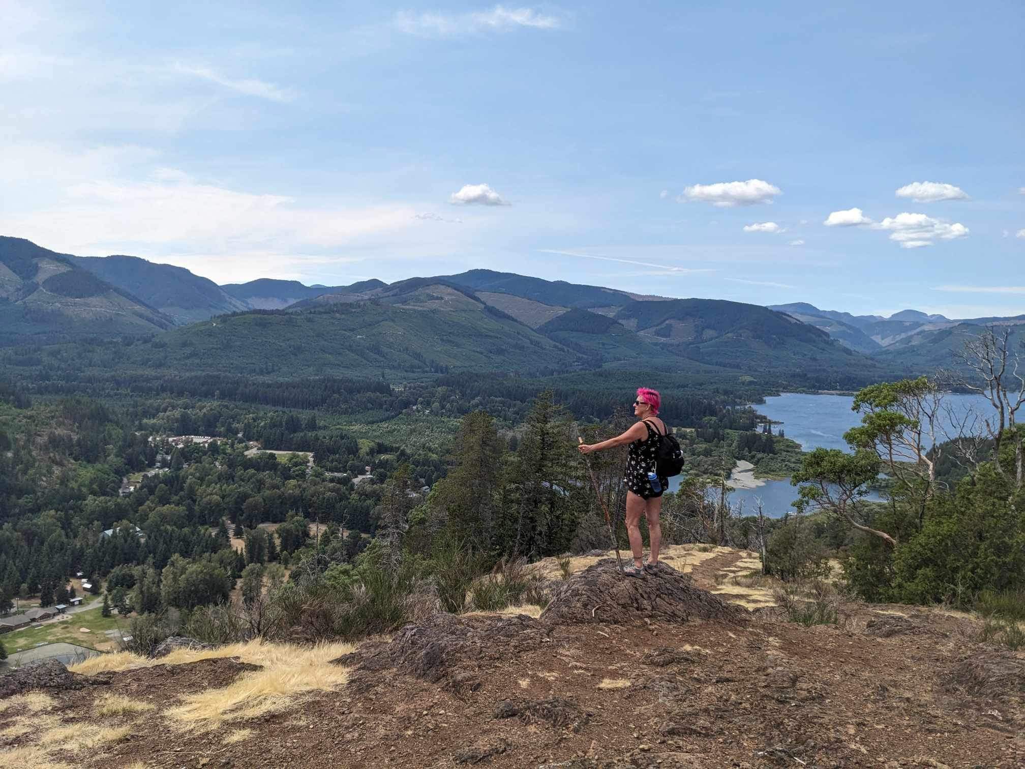 Hiker on a rocky bluff overlooking Mesachie Lake with Lake Cowichan in the distance on Vancouver Island